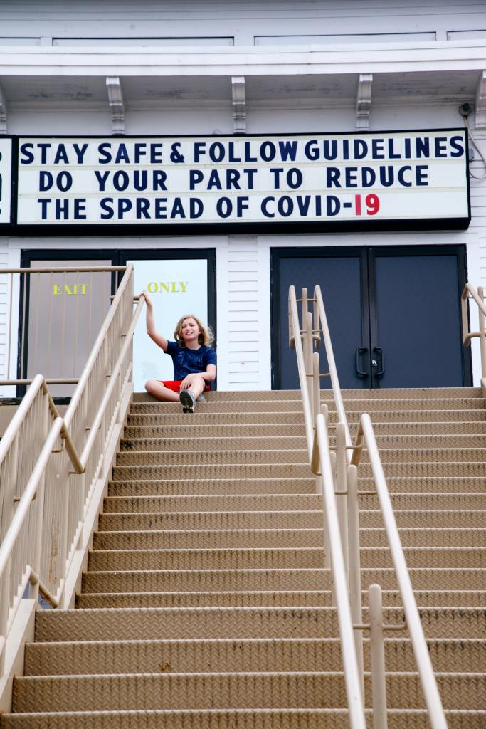 young person sitting by a covid-19 sign