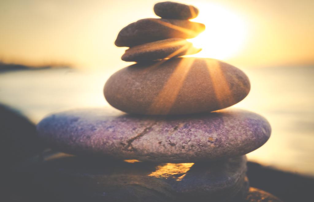 photo of a stack of rocks in nature, with bright rays of sunlight shining