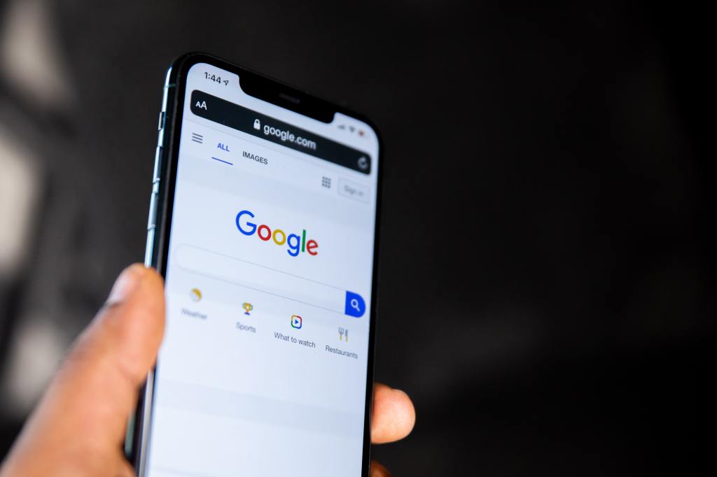 man holding android smartphone perusing the google homepage
