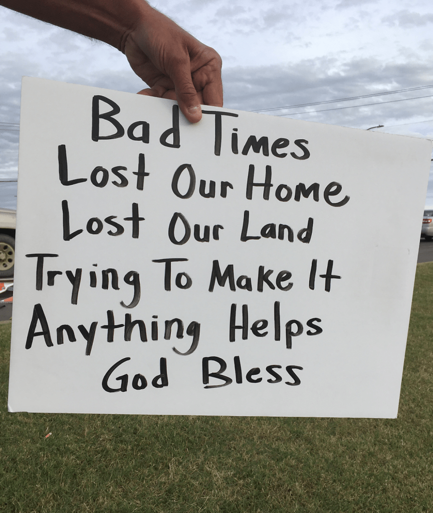 photo of a homeless man holding up a sign