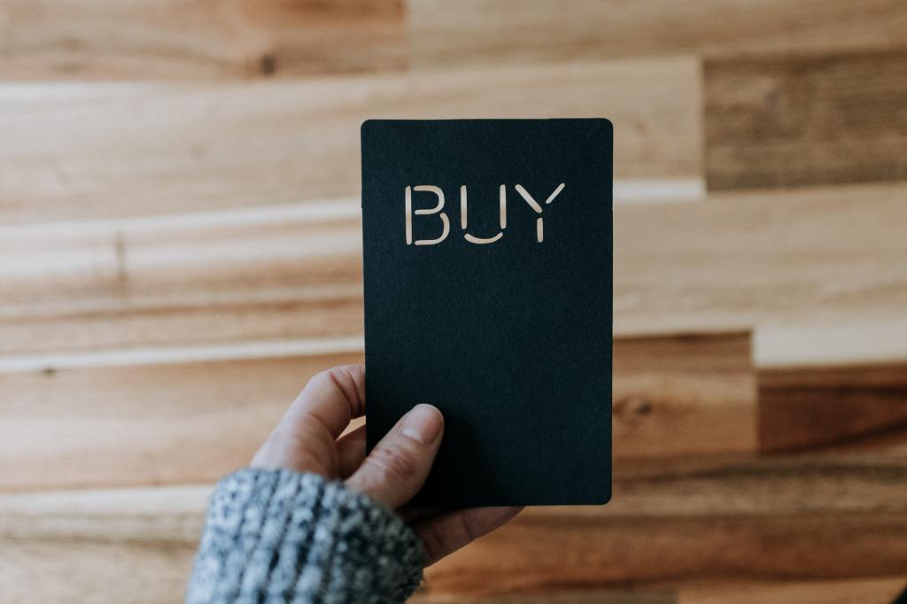 a person holding a card that reads 'buy'