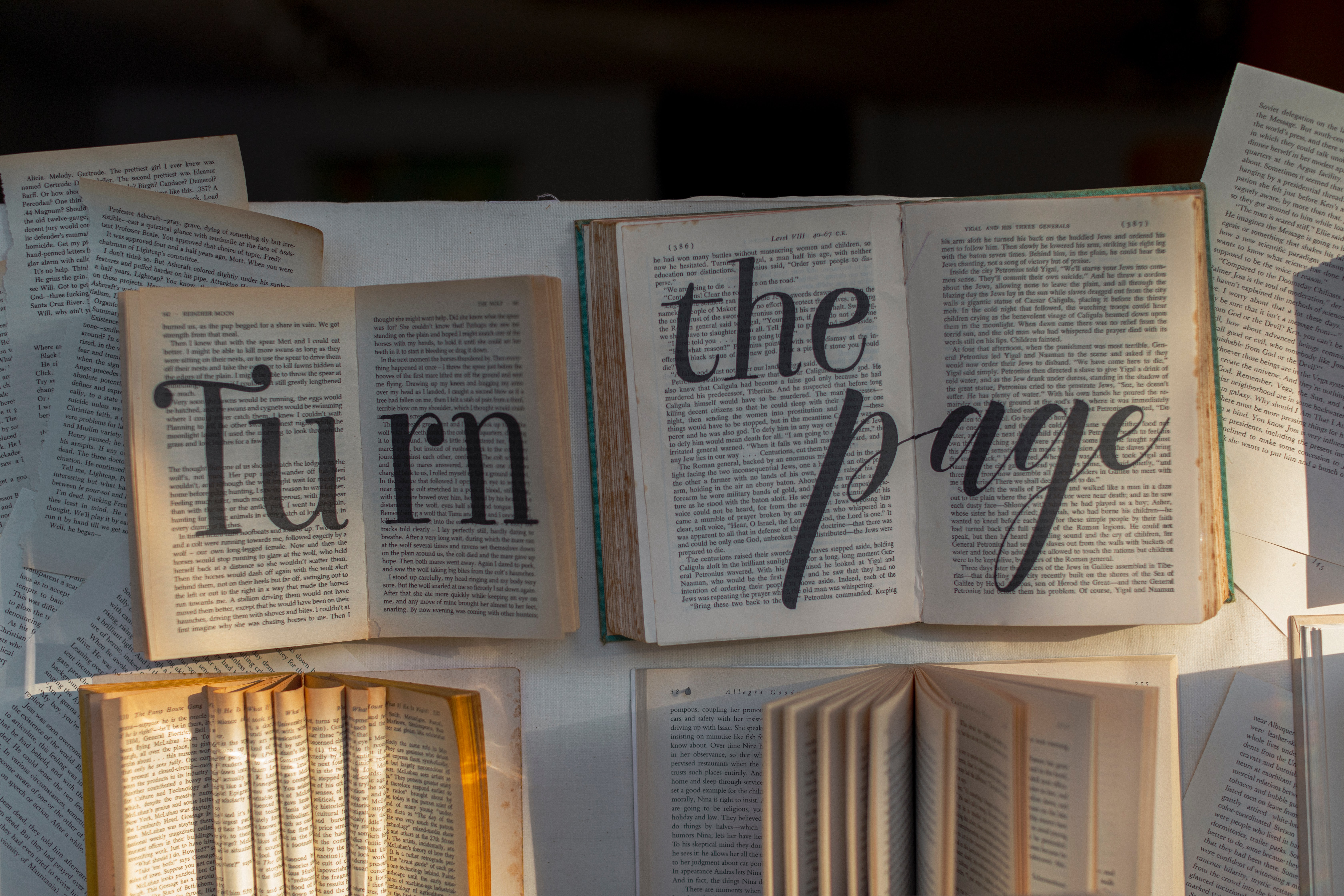 a photo of open books with the text "turn the page" written on the pages