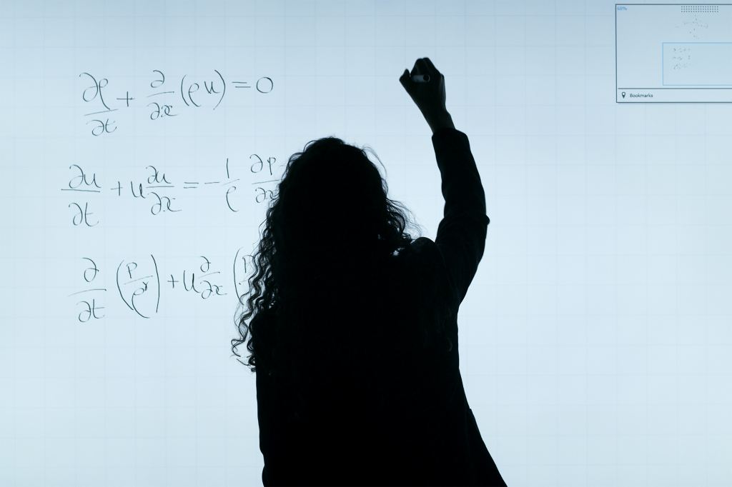 photo of a woman writing equations on a whiteboard