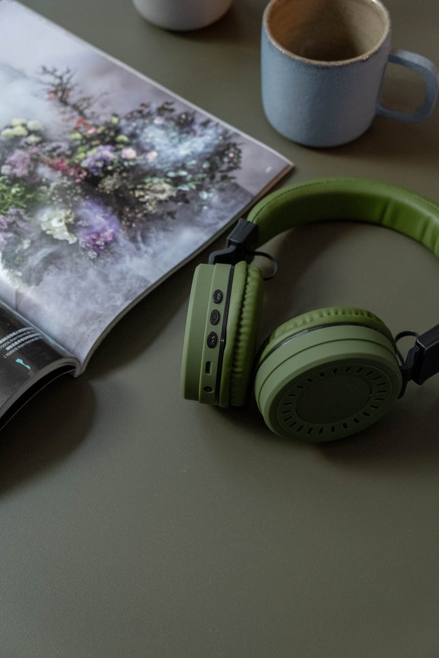 picture of an open magazine, a pair of green headphones, and a ceramic mug arranged aesthetically