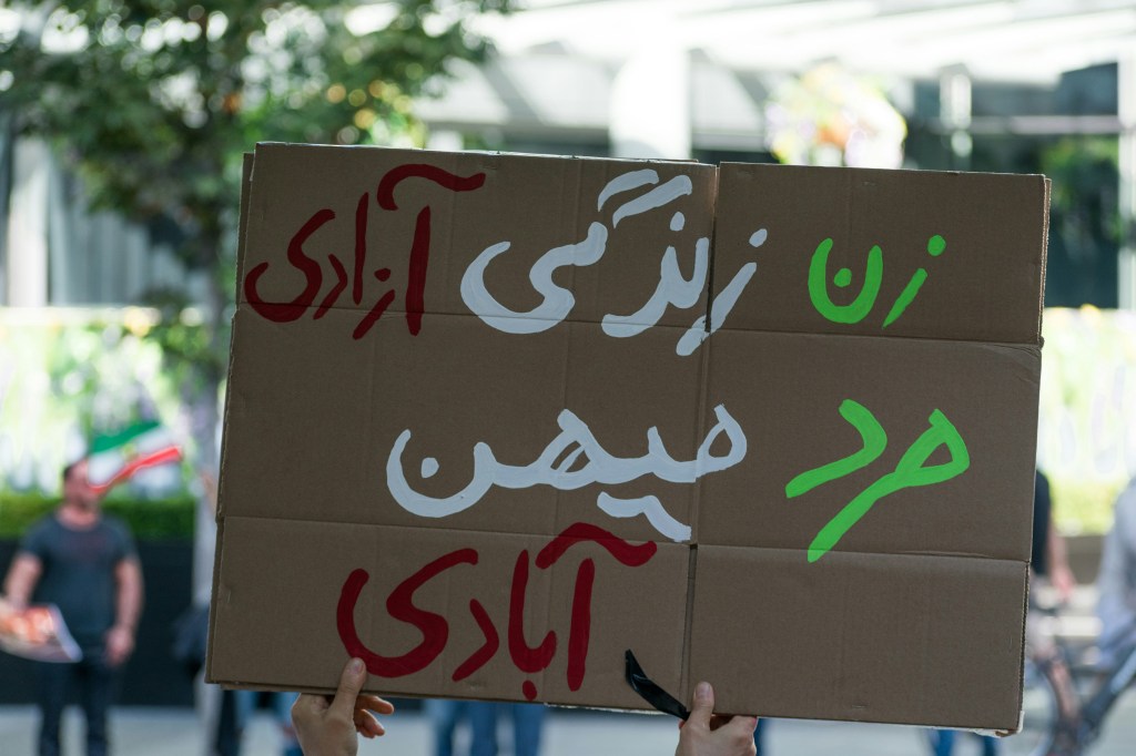 a sign that says "woman, life, freedom" in farsi