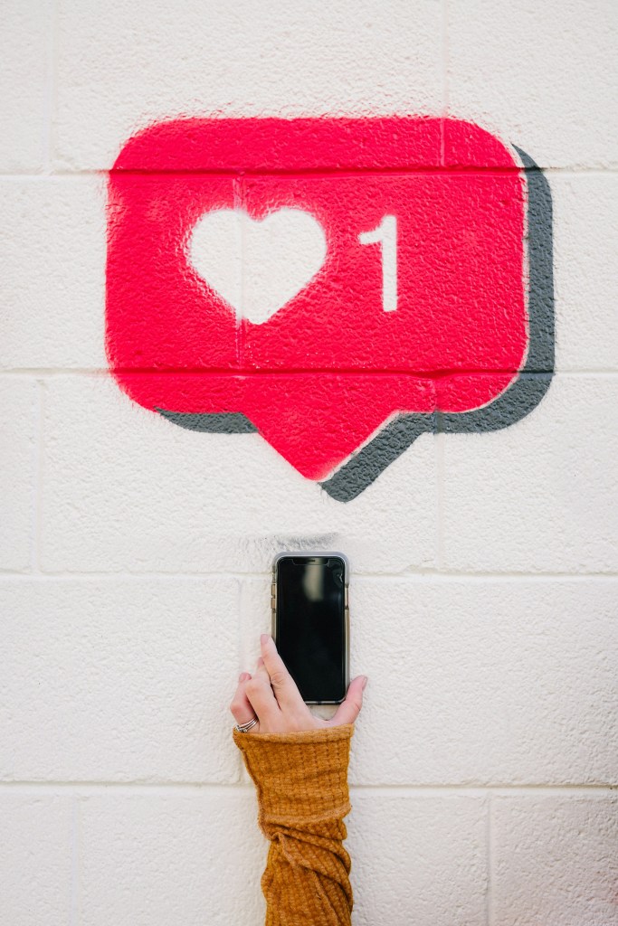 mural of an instagram like icon with a person holding their phone up below it
