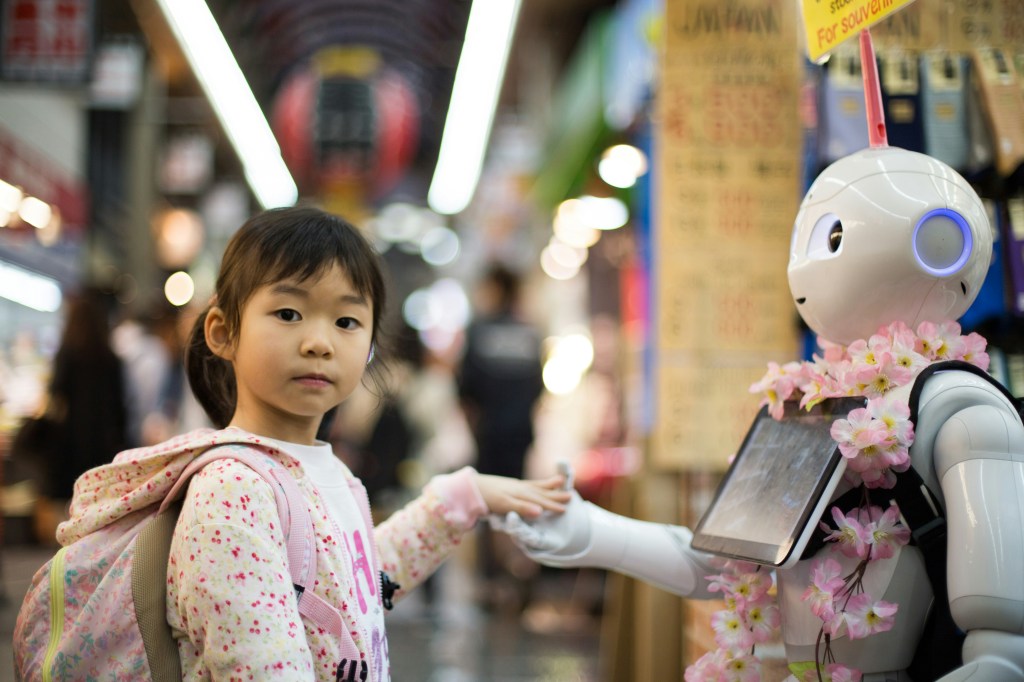 photo of a girl holding hands with a robot
