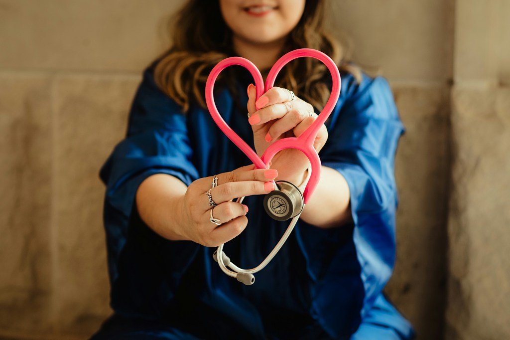 picture of a woman holding a stethoscope and making it into a heart shape